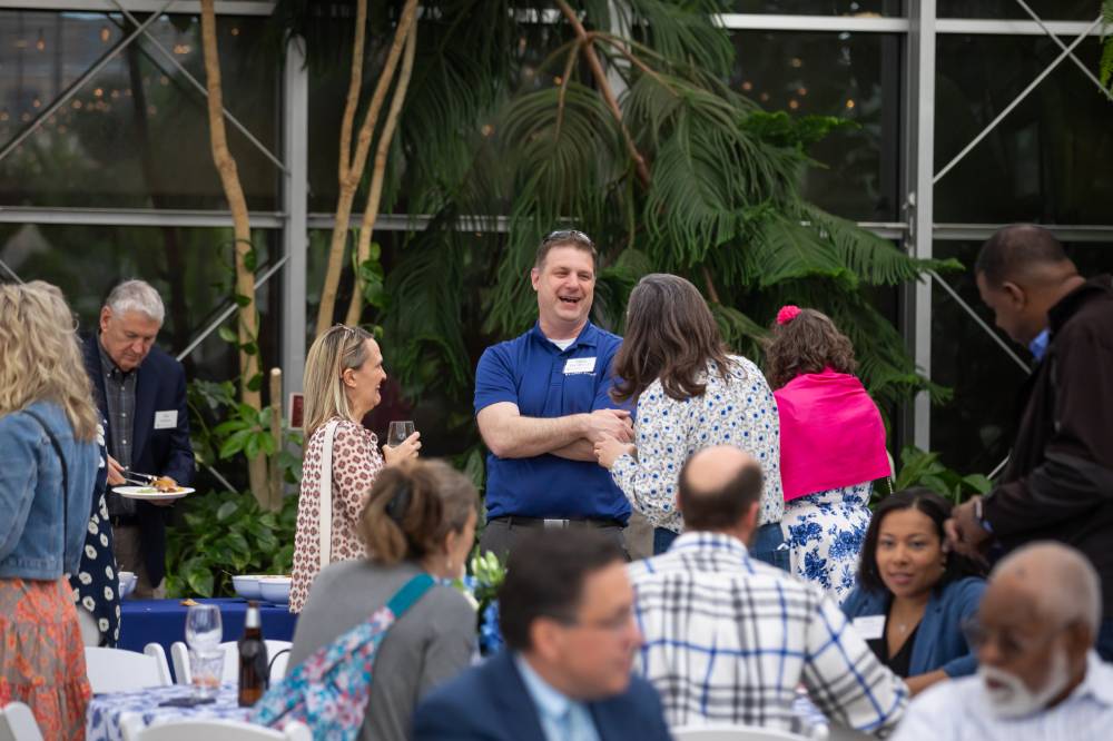 Adam Tate laughing while chatting with two female colleagues